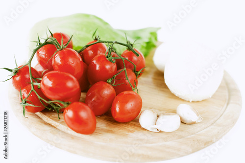 mozzarella, tomatoes, garlic and salad leaf on wooden board