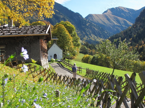 Berghütte mit Kapelle und Frau auf Wanderweg im Herbst