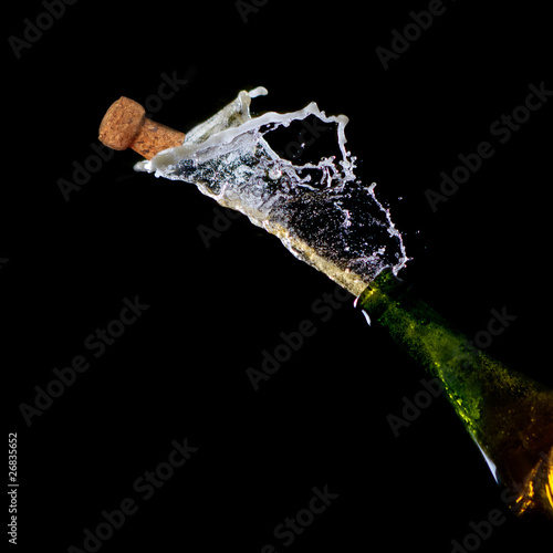 Bottle of Champagne with popping cork and Champagne splash
