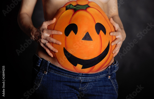 Halloween pumpkin painted on belly of pregnant photo