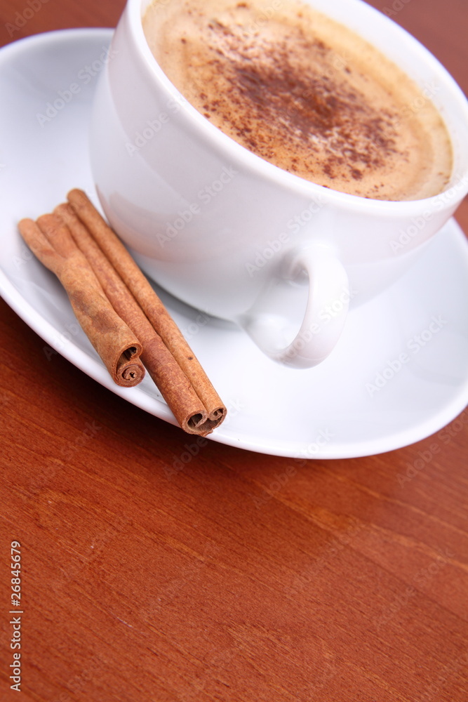 Cup of coffee sprinkled with cinnamon and with cinnamon sticks Cup of coffee sprinkled with cinnamon and with cinnamon sticks
