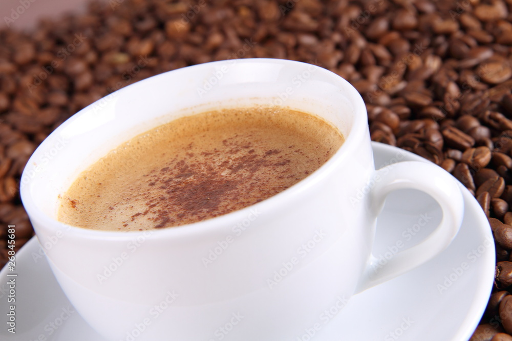 Cup of coffee with cinnamon with coffee beans around it Cup of coffee with cinnamon with coffee beans around it