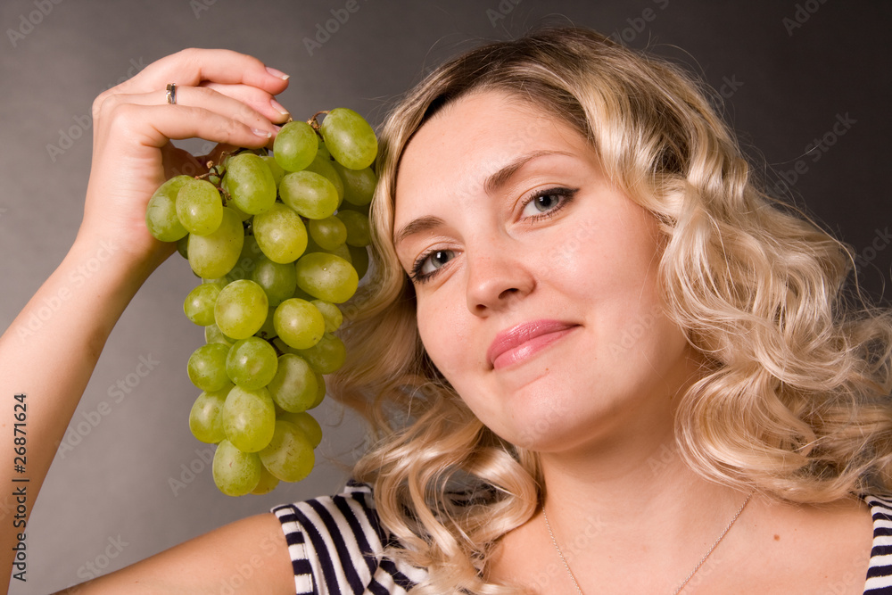 Portrait of beautiful young woman with the cluster of green vine