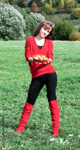 girl with apples in basket on the meadow