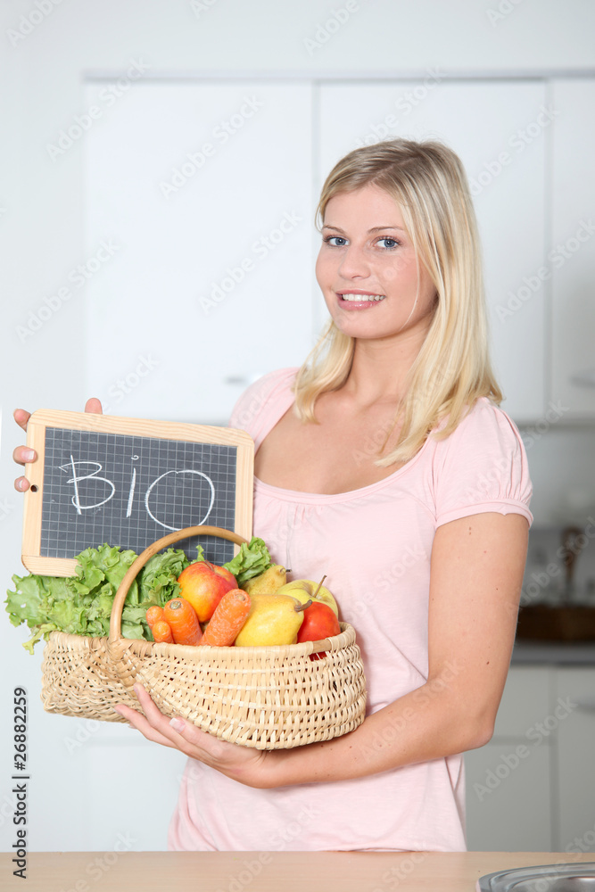 Smiling woman holding basket of organic food Smiling woman holding basket of organic food