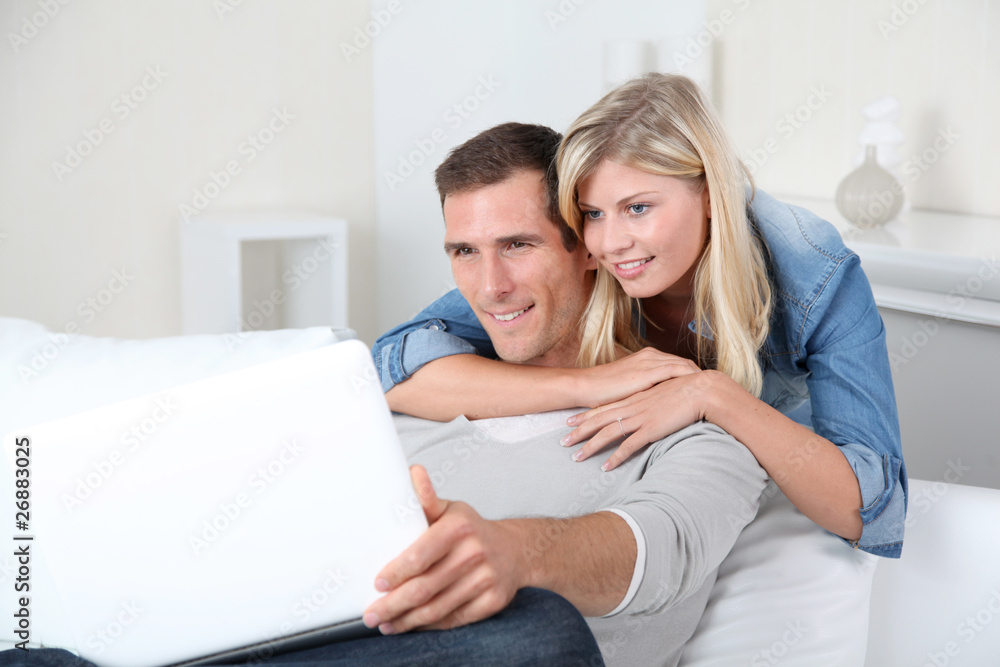 Closeup of couple sitting in sofa surfing on internet Closeup of couple sitting in sofa surfing on internet