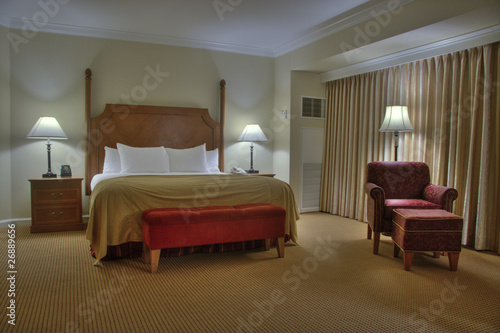 Bedroom with bedside tables armchair lamps and curtain