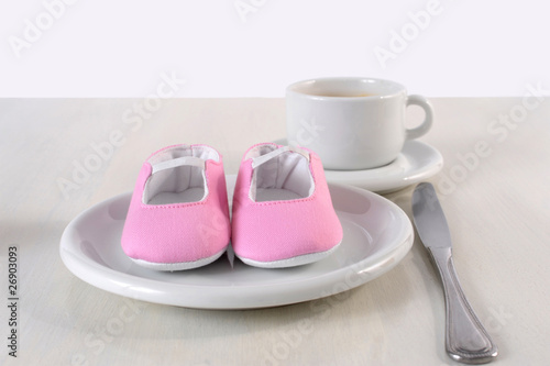 pregnancy concept baby shoes on the breakfeast table