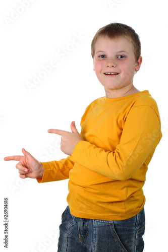 Delighted young boy points finger on something isolated on white