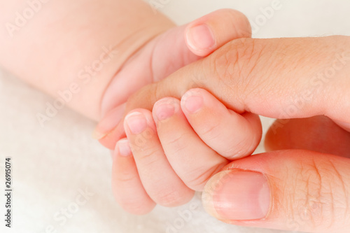 Close-up of baby's hand holding mother's finger