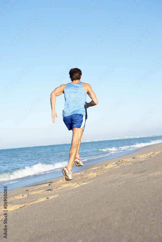 Young Man In Fitness Clothing Running Along Beach Young Man In Fitness Clothing Running Along Beach