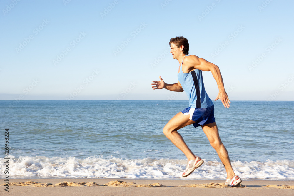 Young Man In Fitness Clothing Running Along Beach Young Man In Fitness Clothing Running Along Beach