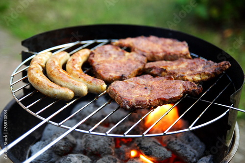 Grill mit Grillfleisch und Bratwurst im Garten