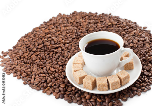 Coffee cup on heap of coffee beans isolated on white