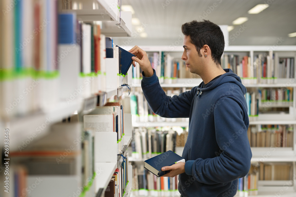 man choosing book in library man choosing book in library