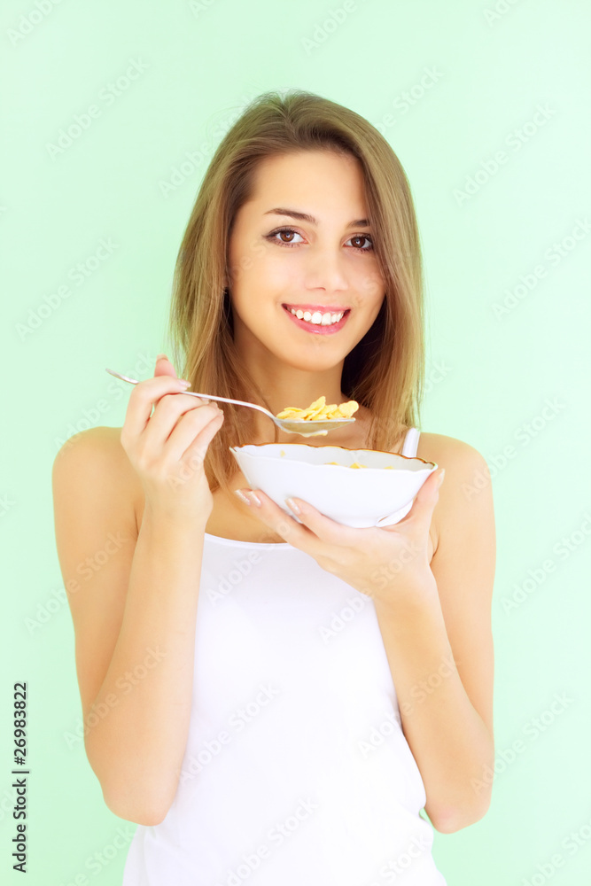 Smiling girl eating cornflakes with a green background Smiling girl eating cornflakes with a green background