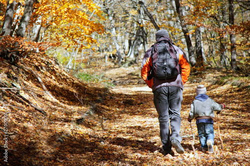 father and son walking in autumn forest