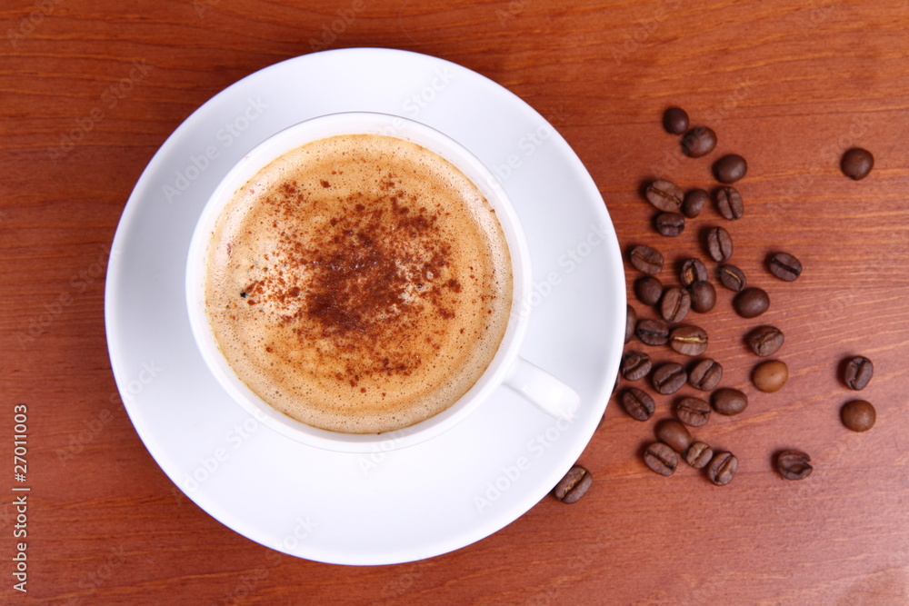 Cup of coffee with cinnamon and coffee beans on a wooden table Cup of coffee with cinnamon and coffee beans on a wooden table