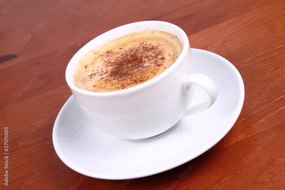 Cup of coffee sprinkled with cinnamon on wooden table Cup of coffee sprinkled with cinnamon on wooden table