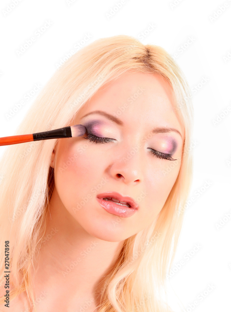 Young woman applying eye shadow, isolated on white