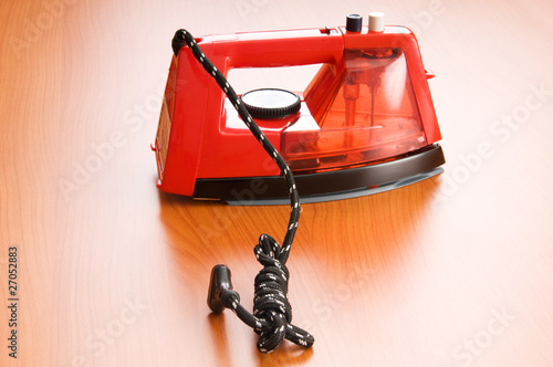 Modern electric iron on the wooden background