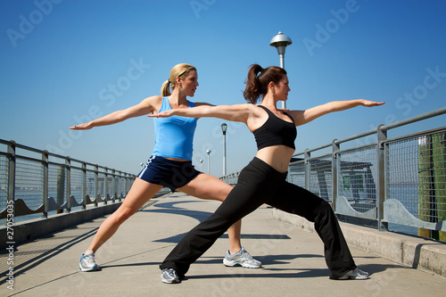 two females stretching on a pier .