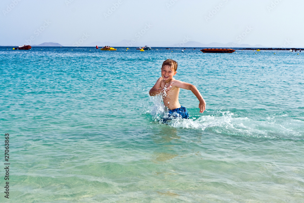 boy has fun running in the water of the ocean