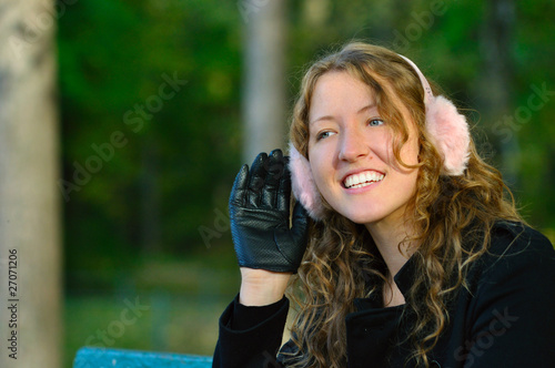 young woman is sitting on the bench in autumn park and listening