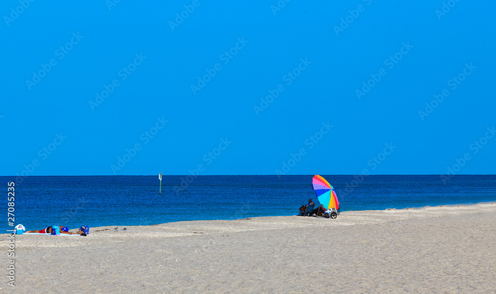 Colorful Beach Umbrella on a sandy beach with blue sky and ocean