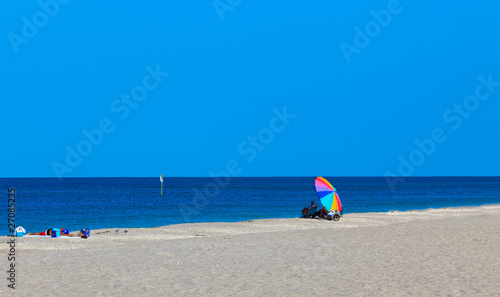 Colorful Beach Umbrella on a sandy beach with blue sky and ocean