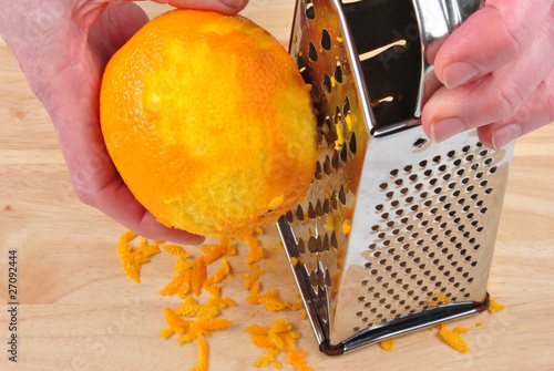 eine Orange wird an einer Reibe abgerieben