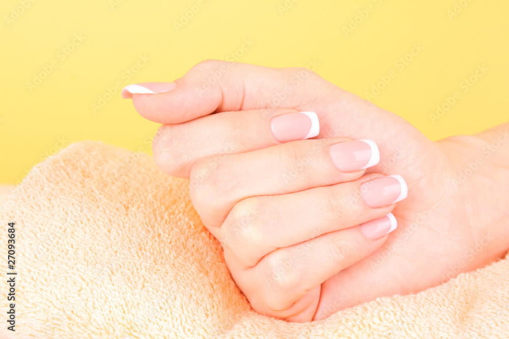 Beautiful woman hands with french manicure on yellow background Beautiful woman hands with french manicure on yellow background
