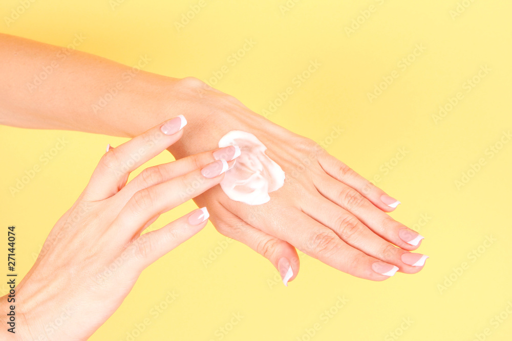 Closeup of beautiful female hands applying hand cream on yellow Closeup of beautiful female hands applying hand cream on yellow