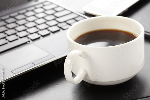 Cup of fragrant coffee on a laptop