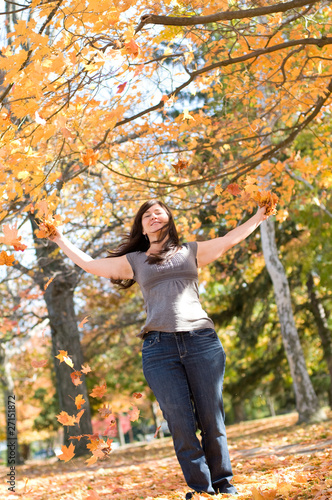 woman in park on autumn day playing with leaves