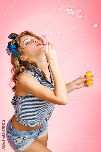 Beauty girl blows bubbles against a pink background