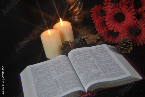 Student studying Bible at christmas by candlelight
