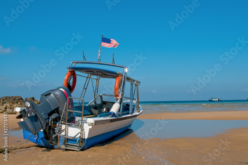 Small boat stranded on the beach with blue sky background
