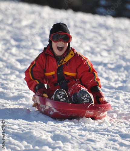 enfant garçon joyeux qui descend avec sa luge