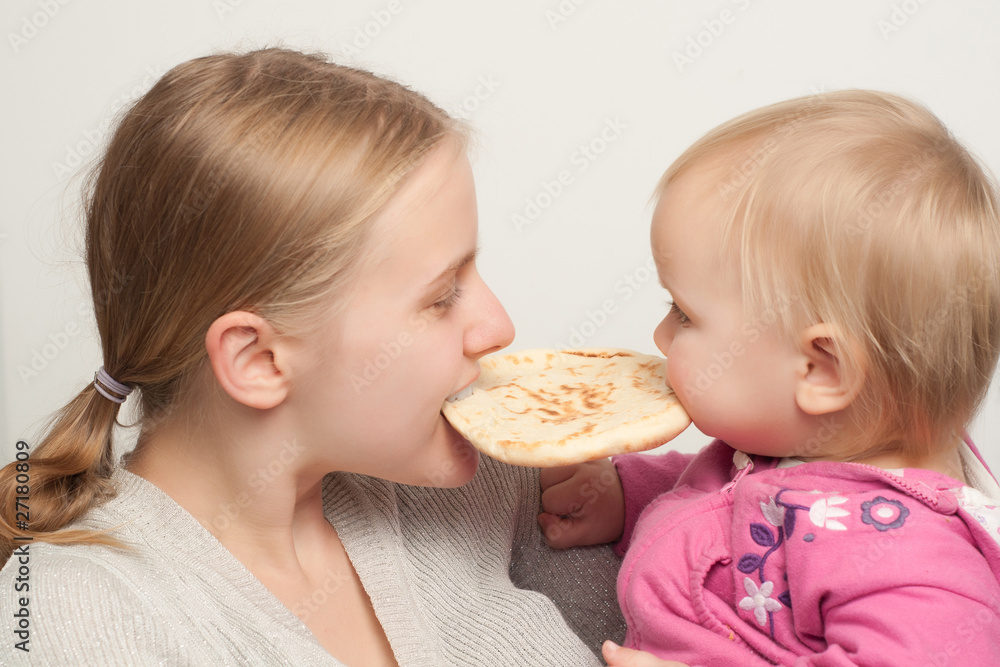 young mother with toddler daughter eat and bitting flatbread young mother with toddler daughter eat and bitting flatbread