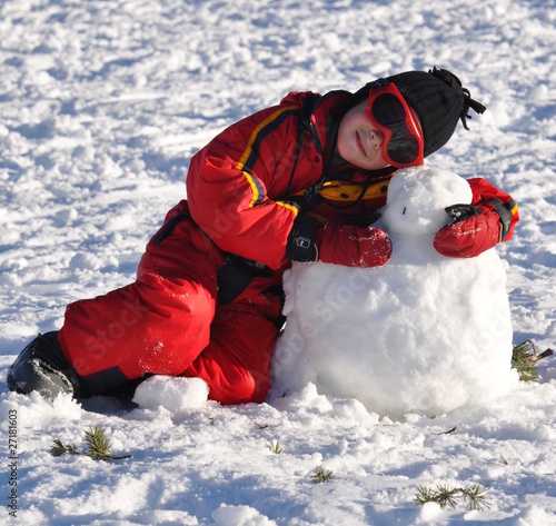 Fotografie sport d'hiver jeune garçon heureux avec son bonhomme de neige