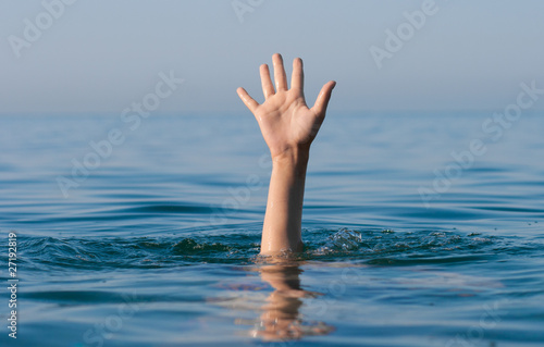 single hand of drowning man in sea asking for help photo