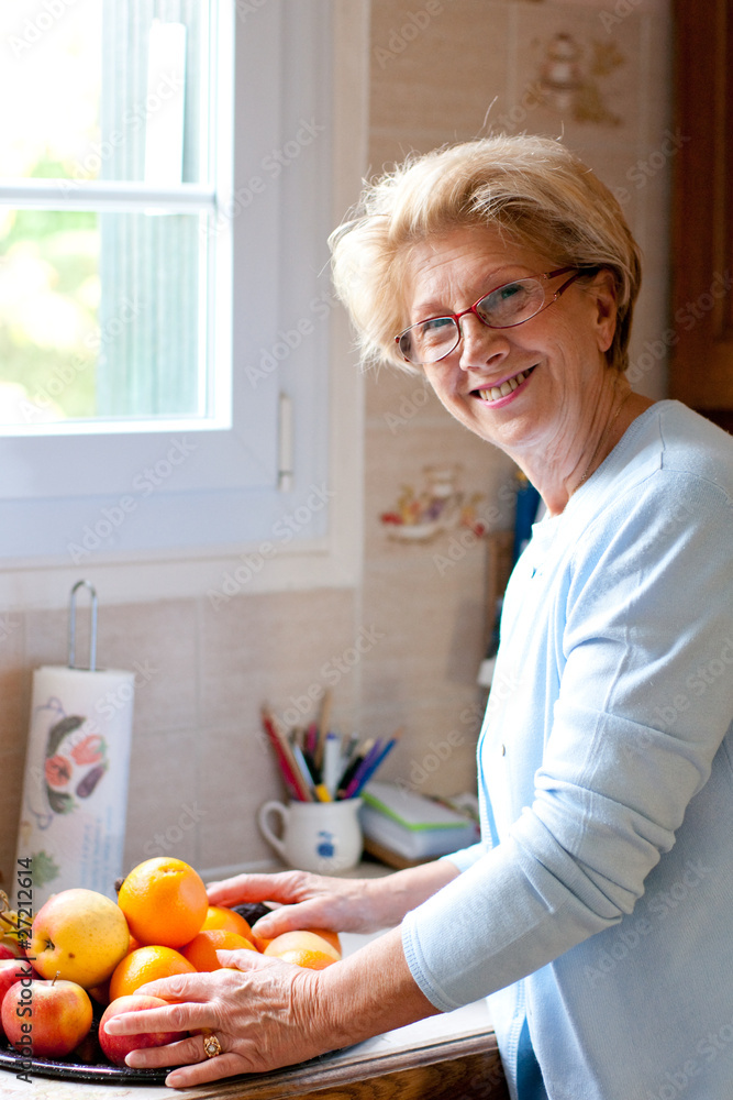 jolie femme retraitée souriante dans sa cuisine jolie femme retraitée souriante dans sa cuisine