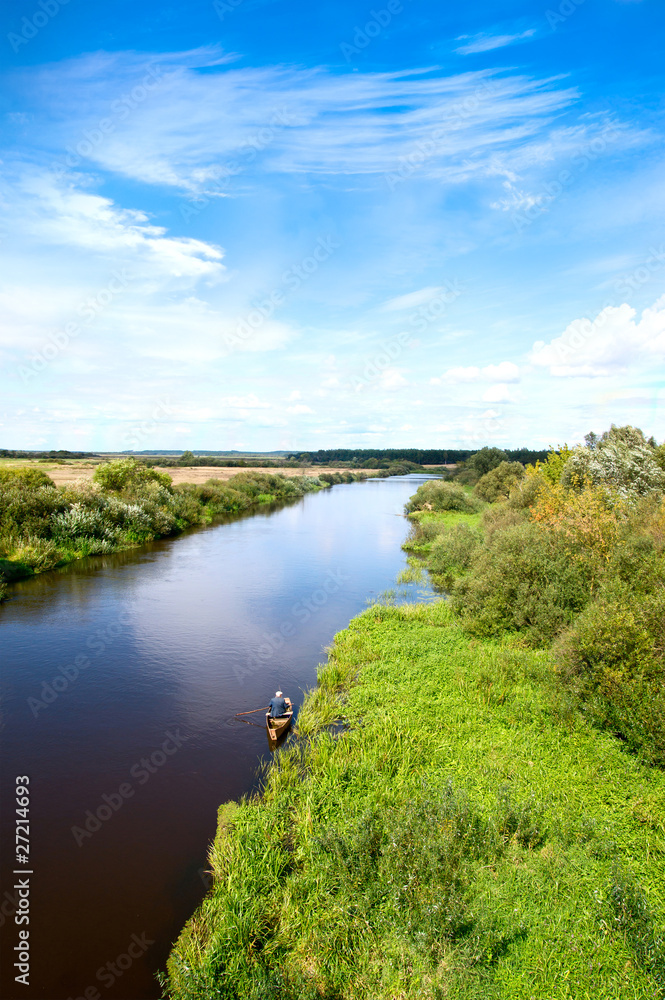 Blue river, cloud sky, green shores and small boat. Blue river, cloud sky, green shores and small boat.