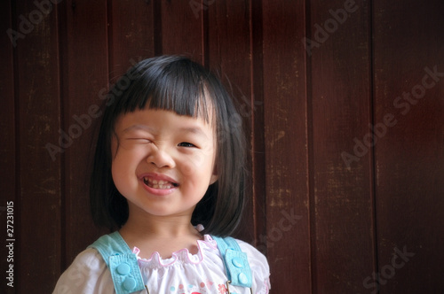 happy cute young girl wink with wooden background