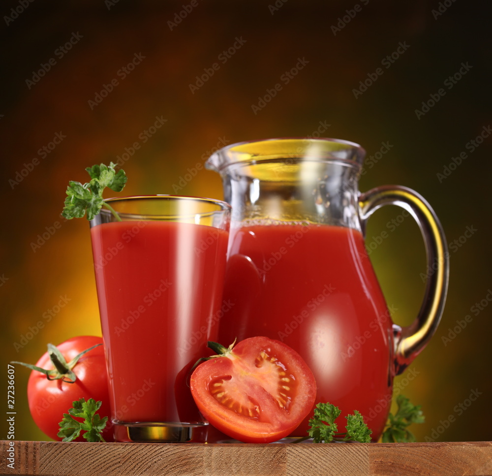 Jug and glass full of tomato juice.