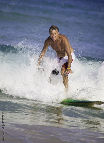Photography sixty-four year old man surfing in hawaii