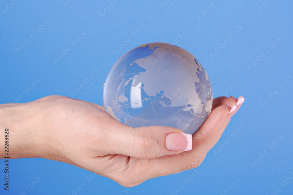 Blue crystal globe in hand on blue Blue crystal globe in hand on blue