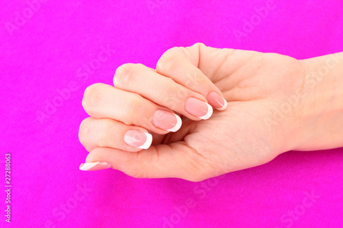 Beautiful woman hand with french manicure on pink background