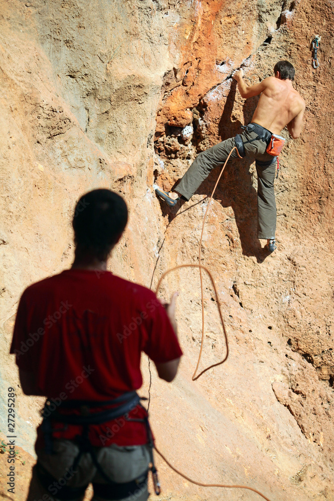 Two rock climbers, one belaying